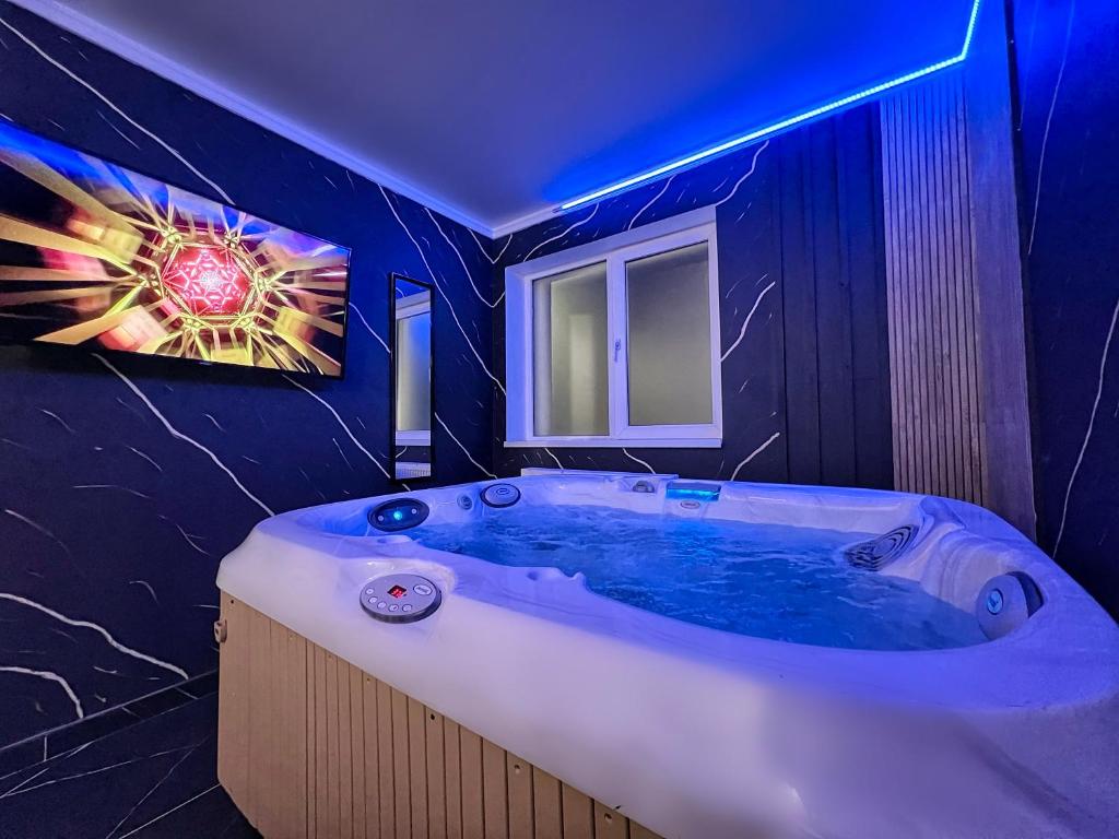 La salle de bains est pourvue d'une grande baignoire avec un éclairage bleu. dans l'établissement Luxor - Jacuzzi&Cozy Apartments, à Sibiu