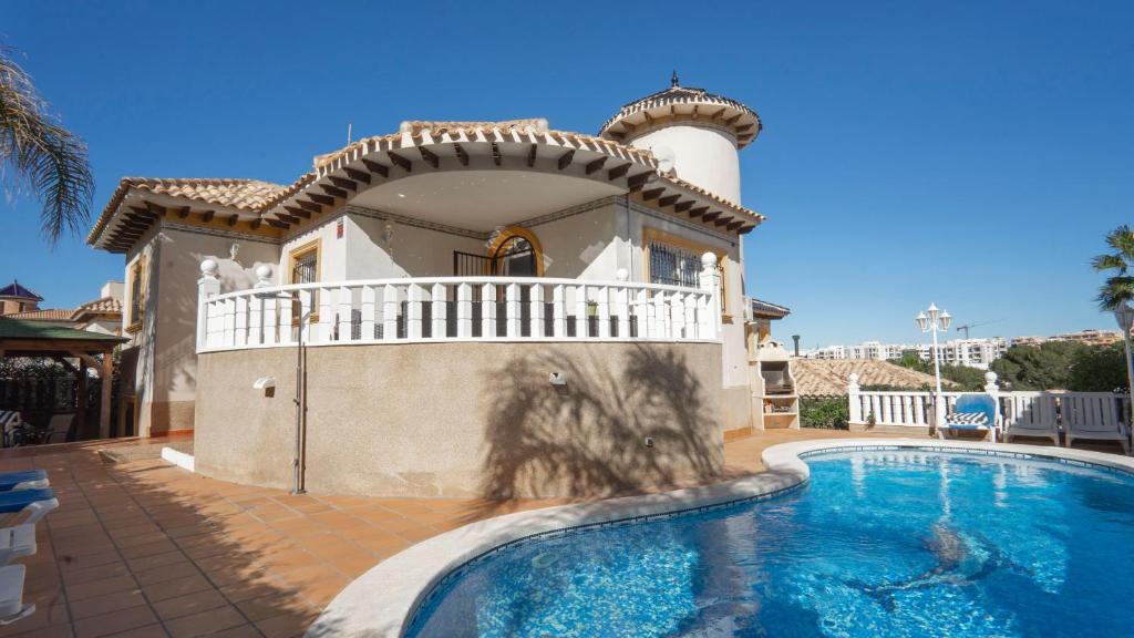 a villa with a swimming pool in front of a house at Amazing villa ideal for golf or family holidays in Villamartin