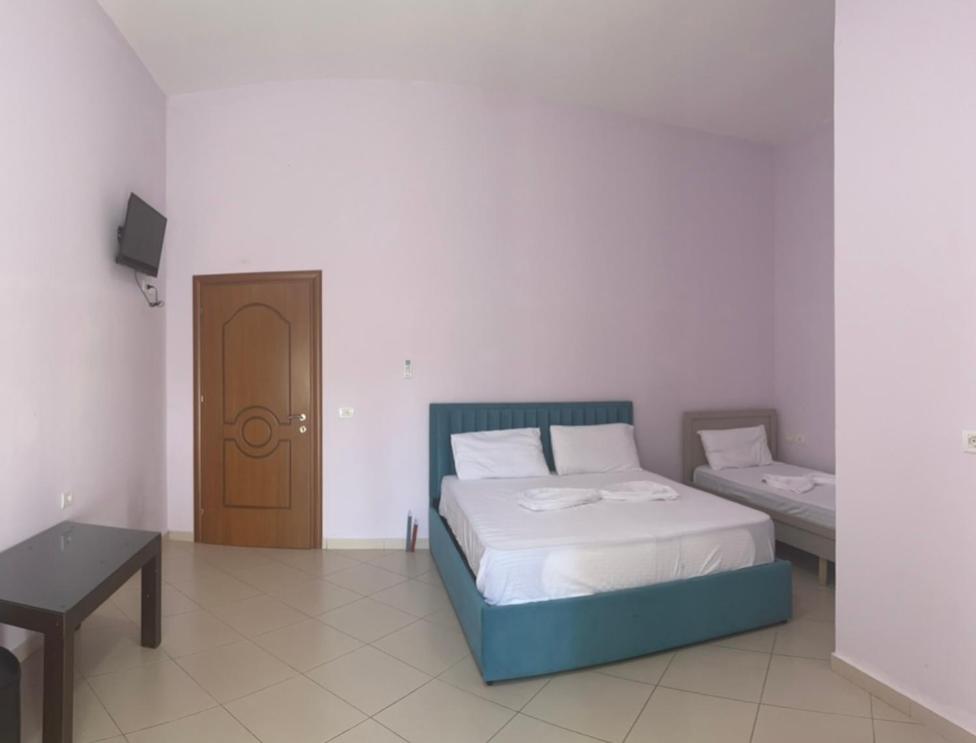Schlafzimmer mit einem Bett, einem Tisch und einer Tür in der Unterkunft Hotel Tani 