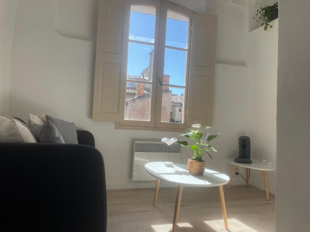 uma sala de estar com um sofá, uma mesa e uma janela em Le Mini - Un voyage en Provence em Aix-en-Provence