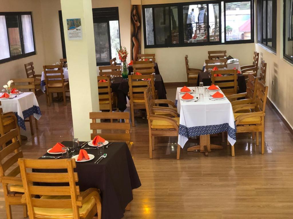 a dining room with two tables and chairs and tablesearcher at One Love Hotel in Kigali