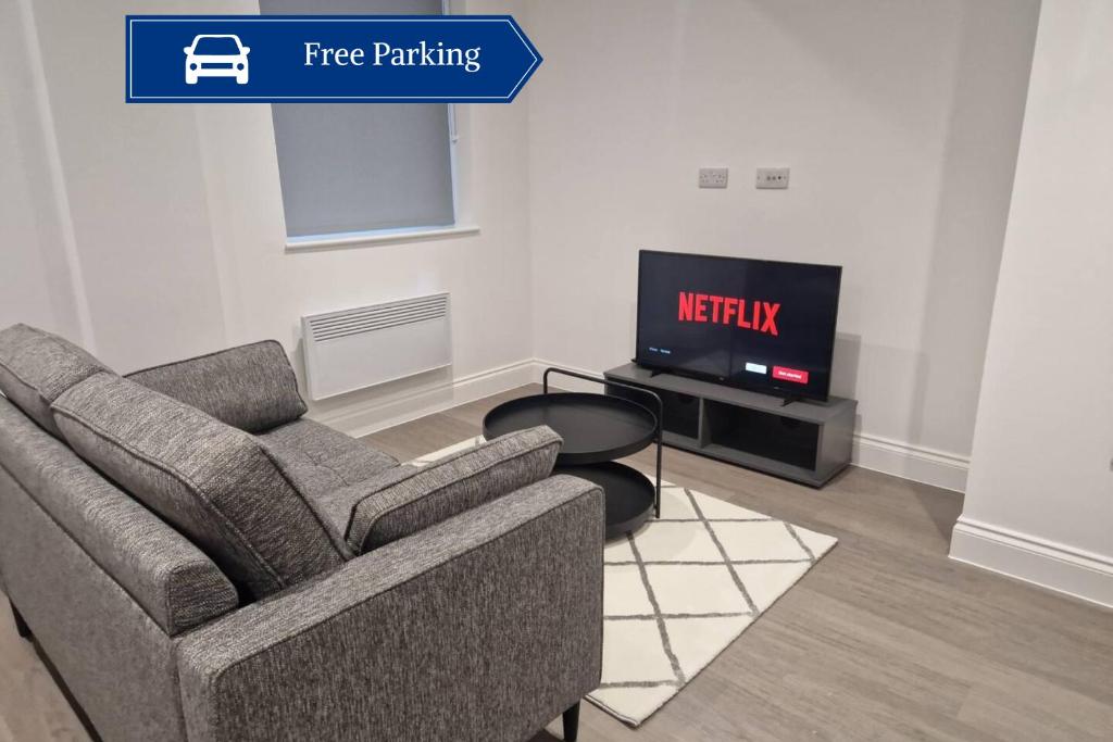 ein Wohnzimmer mit einem Sofa und einem TV in der Unterkunft Wakefield Getaway - Cosy Apt with Free Parking in Wakefield