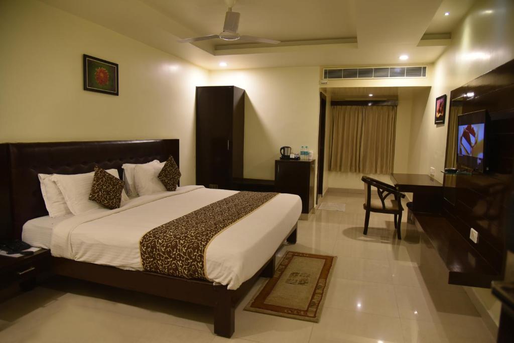 a bedroom with a bed and a desk and a television at Hotel green apple in Visakhapatnam