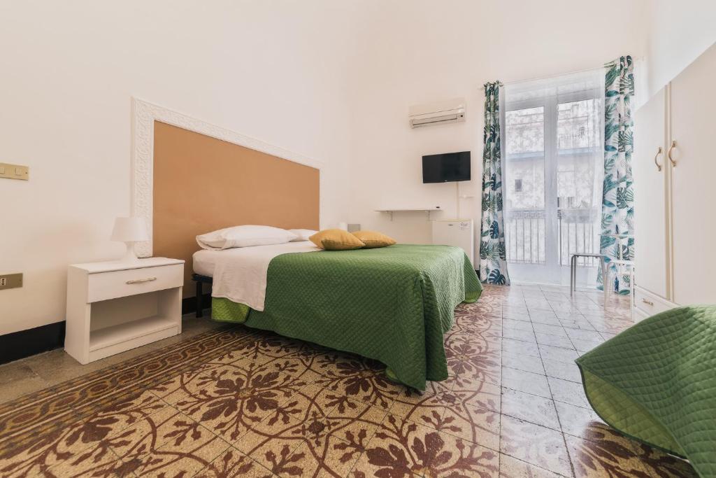 a bedroom with a bed with a green blanket at Voilà Rooms Guest House in Terrasini