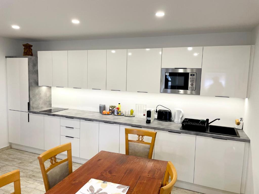 a kitchen with white cabinets and a wooden table at Maul - Lator vendégház in Villány