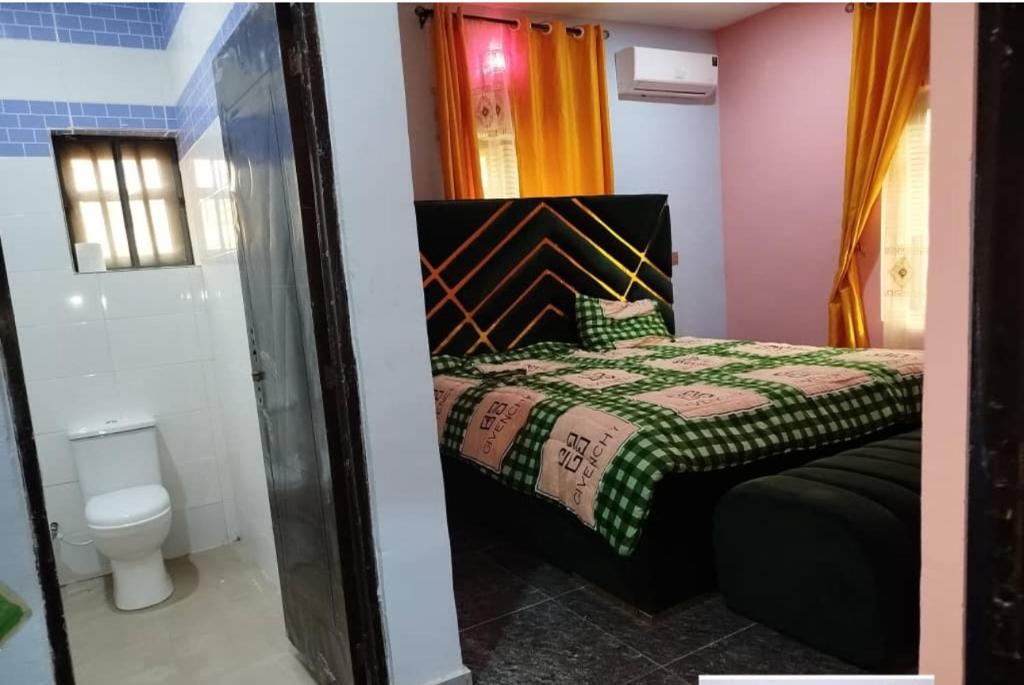 a small bedroom with a bed and a toilet at IOKNC Apartment in Enugu