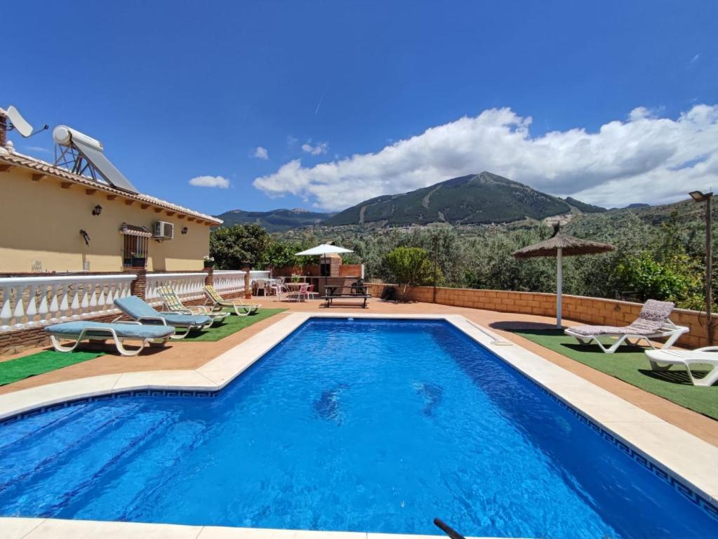 a villa with a swimming pool and mountains in the background at Los Olivos in Málaga