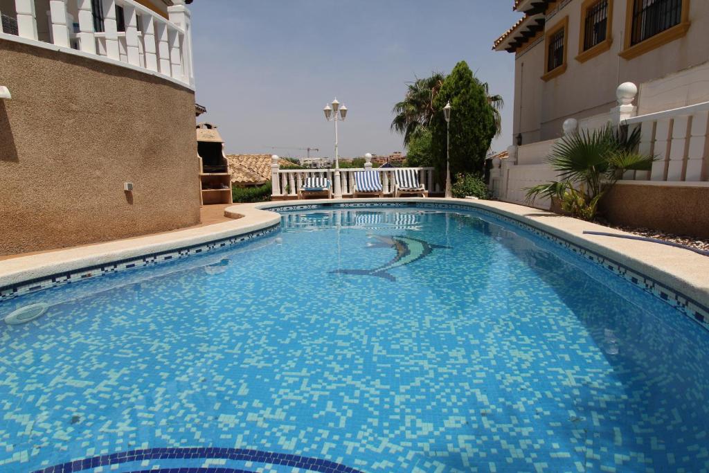 ein großer blauer Pool neben einem Gebäude in der Unterkunft Amazing villa ideal for golf or family holidays in Villamartin