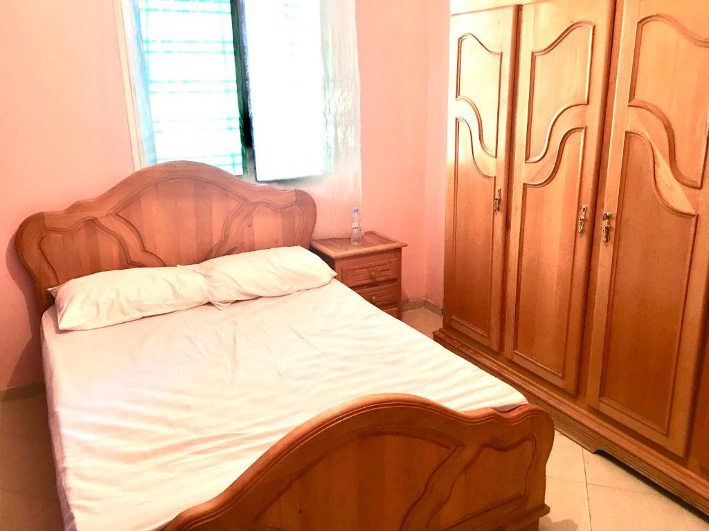 um quarto com uma cama e um armário de madeira em Bel appartement au calme, proche du centre ville em Kenitra
