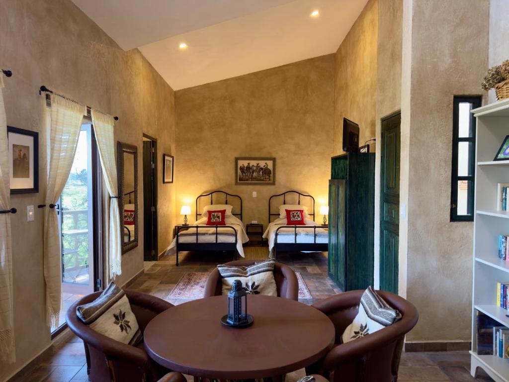 SanteaguedaにあるLoft El Tapatío en Val'Quiricoのベッド2台、テーブル、椅子が備わる客室です。