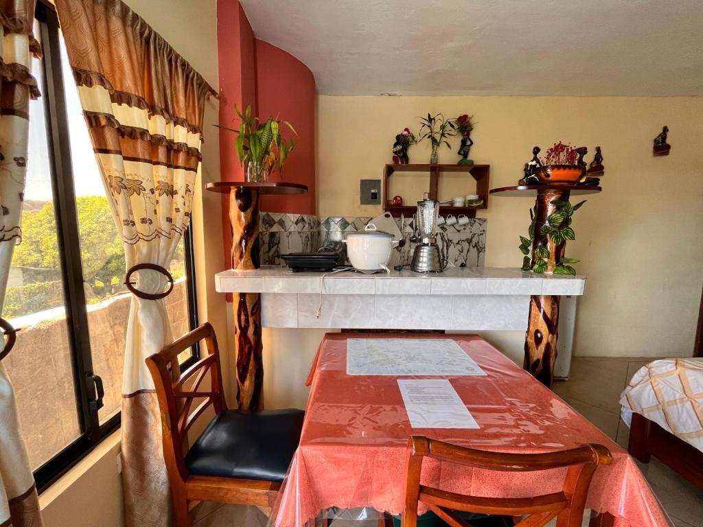 a room with a table and a kitchen with a counter at Casa de Huéspedes Paola in Puerto Baquerizo Moreno