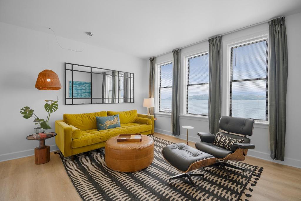 a living room with a yellow couch and two chairs at Norblad Hotel in Astoria, Oregon
