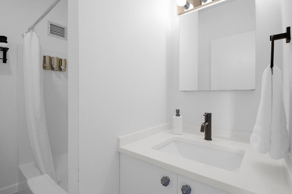 a white bathroom with a sink and a shower at Norblad Hotel in Astoria, Oregon