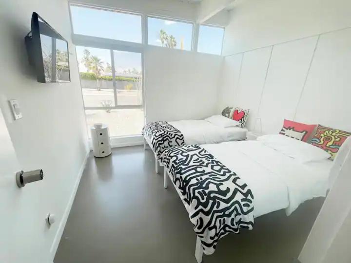 a bedroom with two beds and a tv and a window at Super Cute room in Architectural Home in Palm Springs
