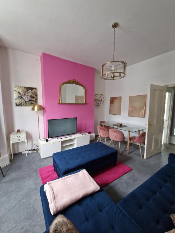 a living room with a blue couch and a pink wall at Lovely One Bed Apartment in St Leonards in St. Leonards