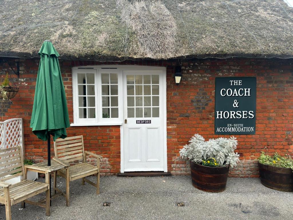 um edifício de tijolos com uma porta branca e uma placa em The Coach and Horses em Winchester