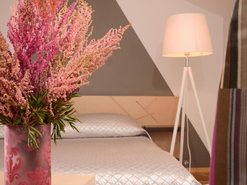een vaas met roze bloemen op een tafel naast een bed bij Mans Nams - self check in hotel in Saldus