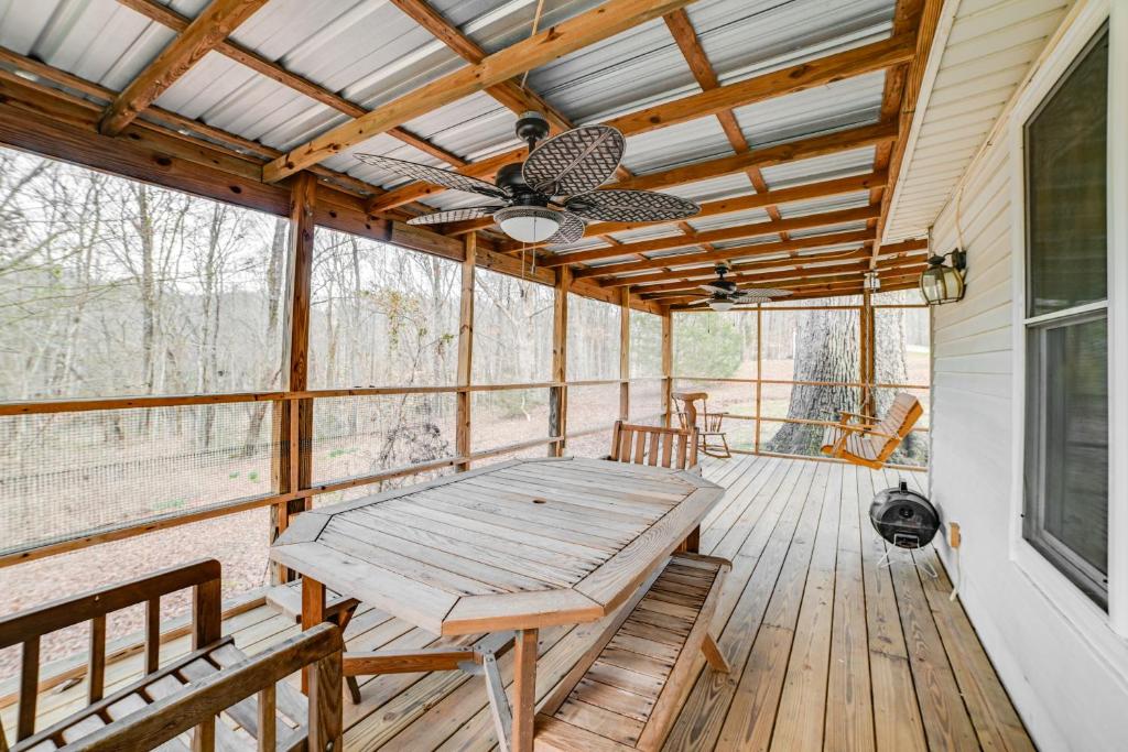 une véranda avec une moustiquaire, une table en bois et un ventilateur de plafond dans l'établissement Peaceful Cottage with Yard 2 Mi to Kentucky Lake!, 