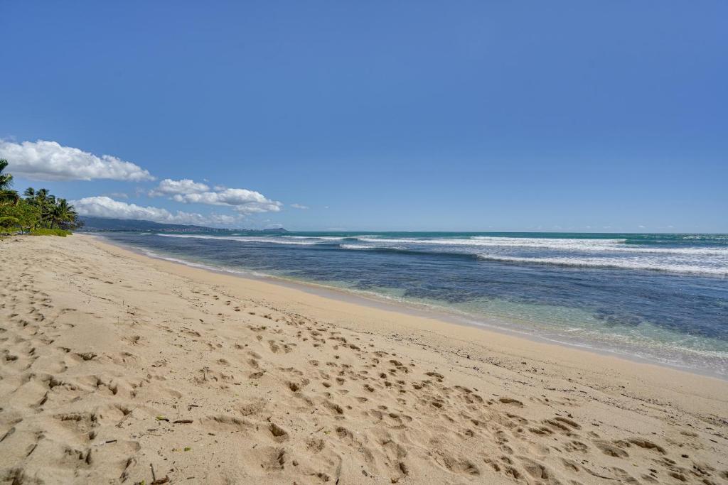 a beach with footprints in the sand and the ocean at Pet-Friendly Ewa Beach Apartment about 1 Mi to Ocean! in Kapolei