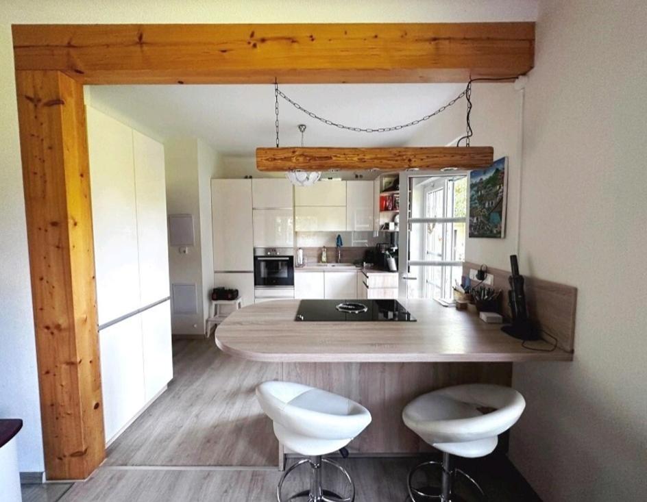 a kitchen with a table and two white stools at Ferienwohnung im Grünen am Rande von Dresden in Radeberg