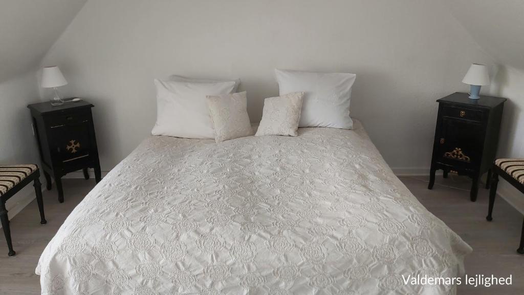 - un lit blanc avec 3 oreillers et 2 tables de nuit dans l'établissement Døssinghus Holiday Apartments, à Kjellerup