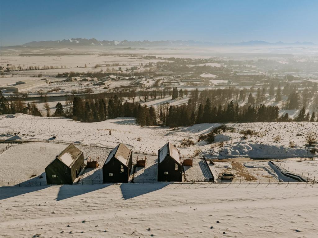 um grupo de casas no topo de uma colina coberta de neve em Stodoły z widokiem em Nowy Targ