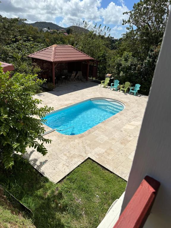 a swimming pool with chairs and a gazebo at Kama in Sainte-Luce