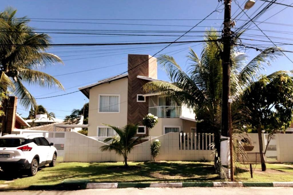 una macchina bianca parcheggiata di fronte a una casa di CASA DE PRAIA NO CONDOMÍNIO PARAÍSO, GUARAJUBA a Camassari