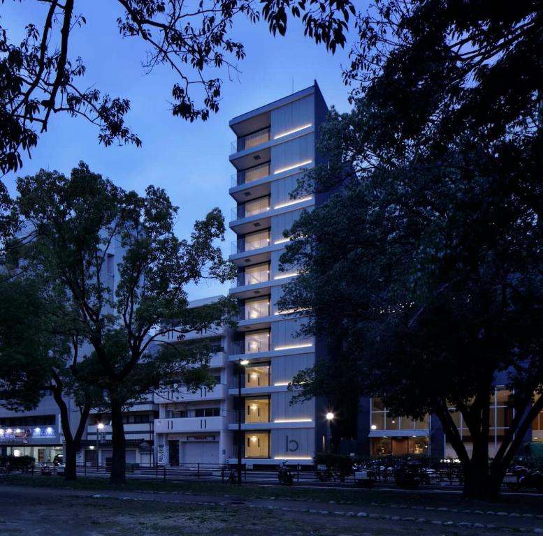 廣島的住宿－bHOTEL Heiwaoodori 401 - Brand New Apt Famous Hiroshima Dori 6ppl，一座高大的公寓楼,晚上灯光照亮
