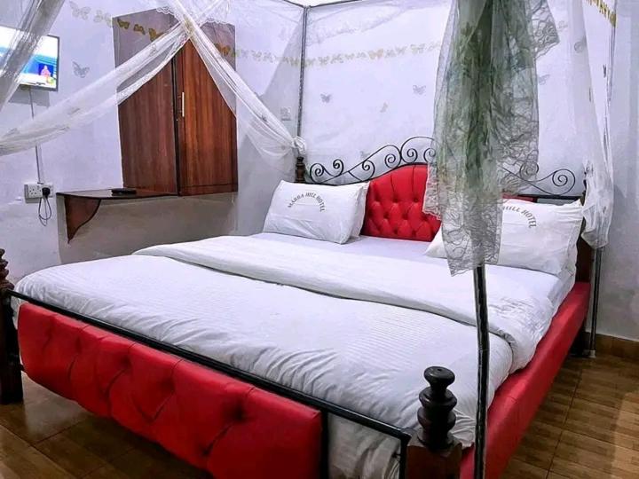 1 dormitorio con cama roja y blanca con dosel en Js Hotel & Accommodation, en Nakuru