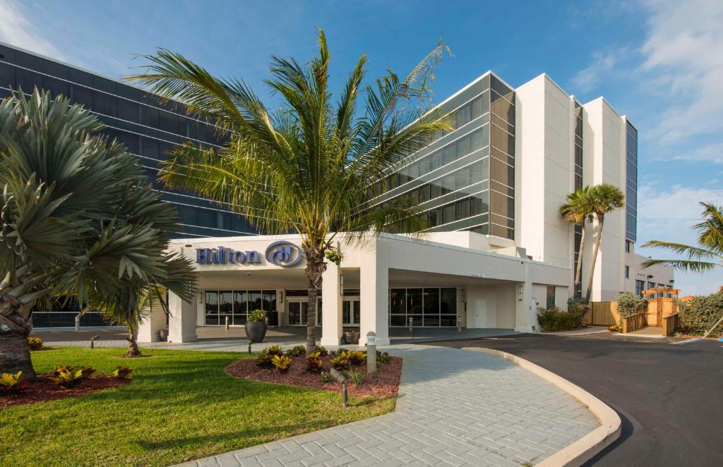 a building with a palm tree in front of it at Hilton Cocoa Beach Oceanfront in Cocoa Beach