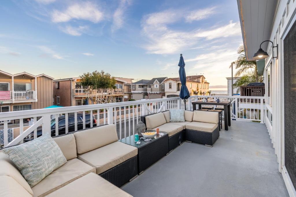 a balcony with couches and an umbrella at Ocean Breeze II by AvantStay Steps to the Beach in Newport Beach