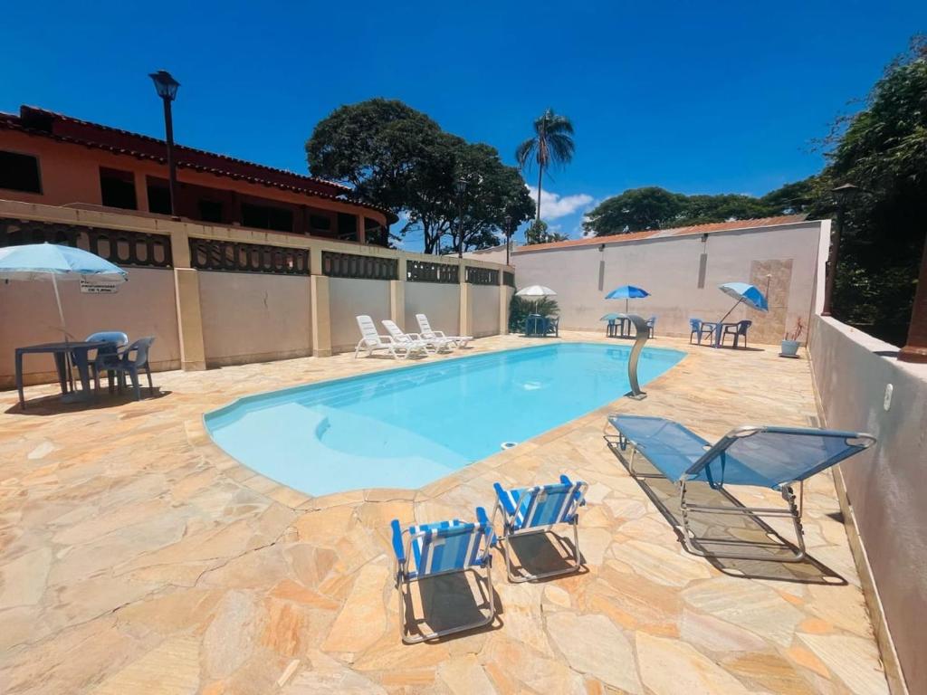 une piscine avec chaises et parasols sur un patio dans l'établissement Pousada Terraço, à Socorro