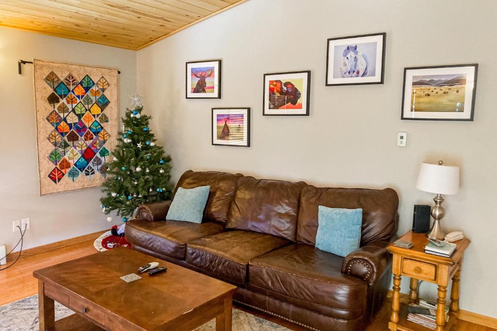 sala de estar con sofá de cuero marrón y árbol de Navidad en The Mountain Artist's Retreat, en Florissant
