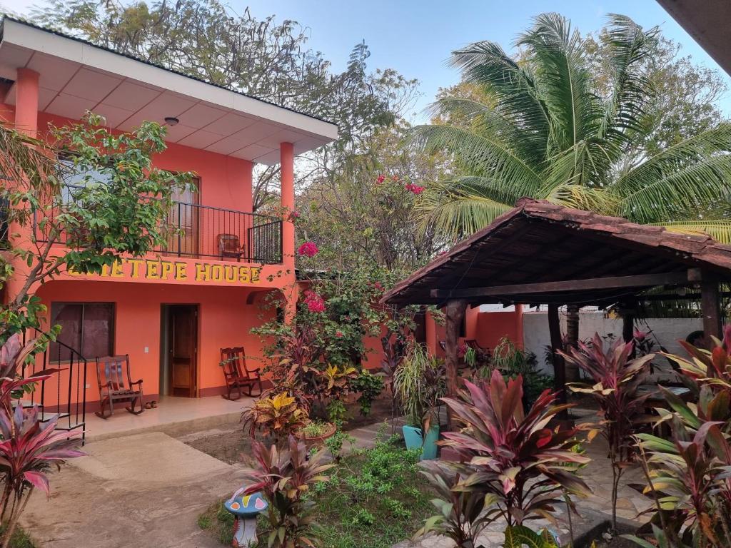 an orange building with a balcony and a palm tree at Ometepe House in Moyogalpa