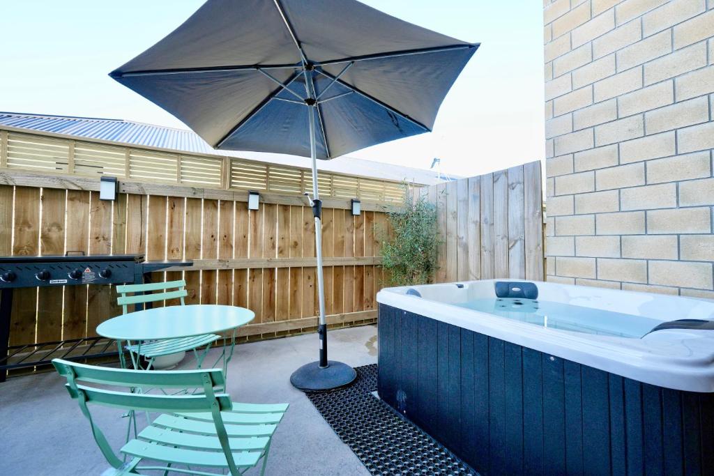 a patio with a tub and a table and an umbrella at Two-Bedroom House with Jacuzzi at Rototuna! in Hamilton