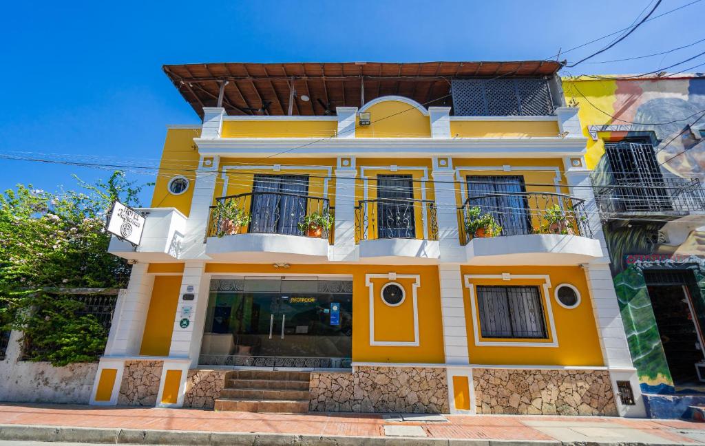 a yellow and white house with a balcony at Hotel Tayromar in Santa Marta