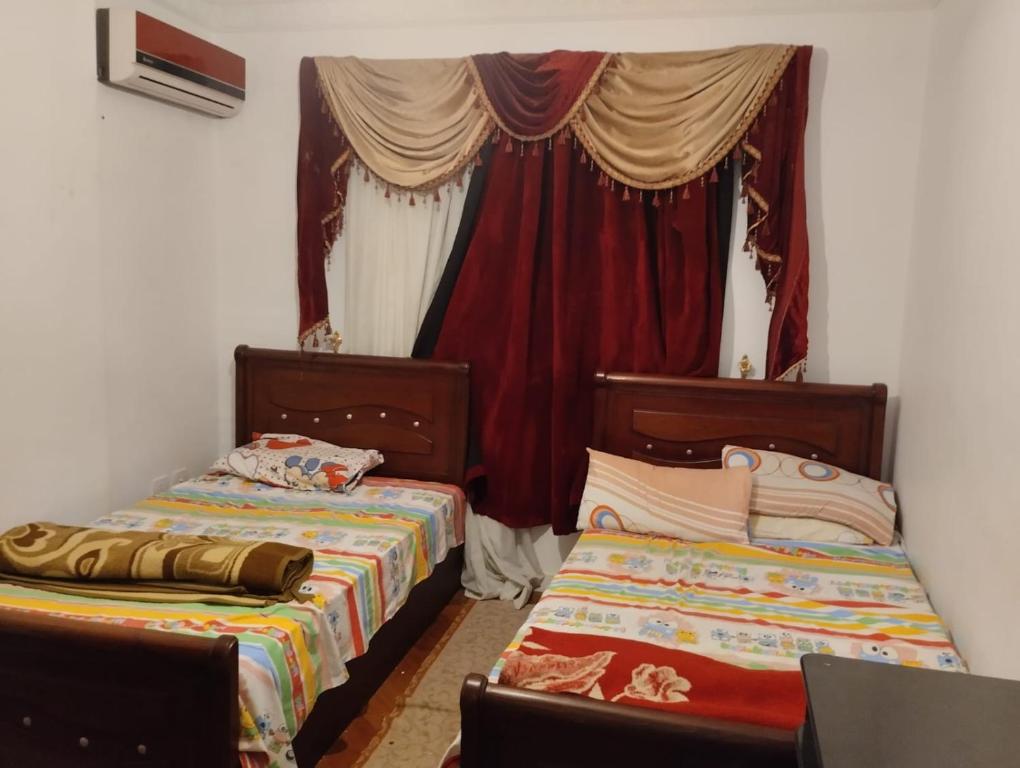 a bedroom with two beds and a window with curtains at عباس العقاد in Cairo