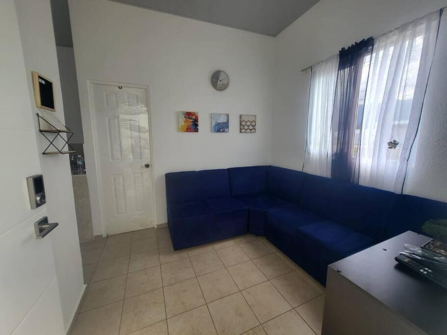 Max´s House في Ahuachapán: أريكة زرقاء في غرفة بها نافذة