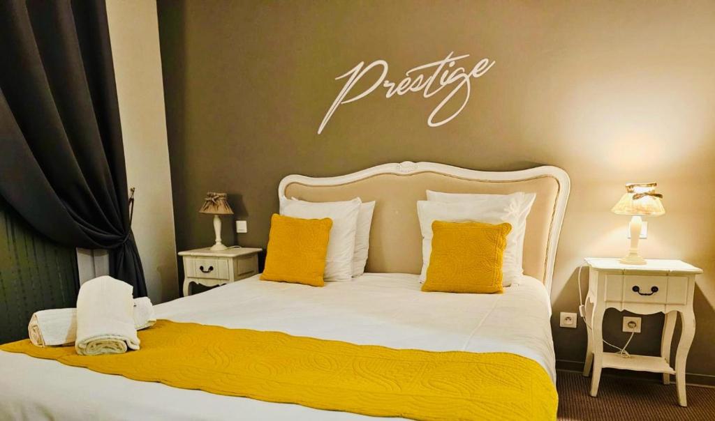ein Schlafzimmer mit einem großen Bett mit gelben Kissen in der Unterkunft Hôtel Les Demoiselles in Essoyes