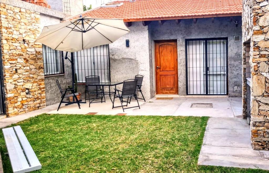 une terrasse avec une table, des chaises et un parasol dans l'établissement Casa 6 pers., à Mendoza