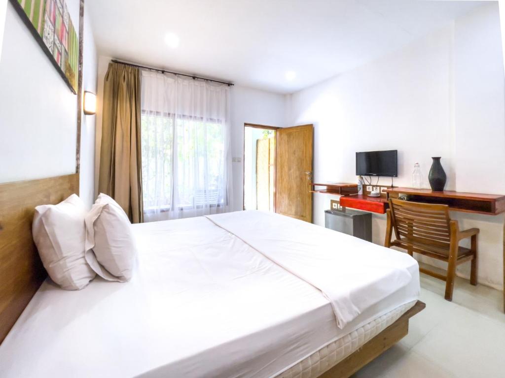 a bedroom with a large white bed and a desk at Lara Homestay in Kuta Lombok