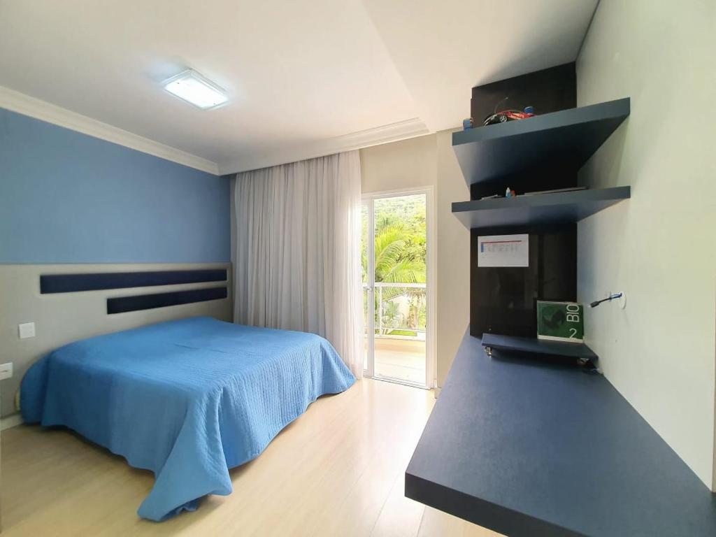 a bedroom with a blue bed and a window at Demi-suíte privativa em casa familiar 2 in Itajaí
