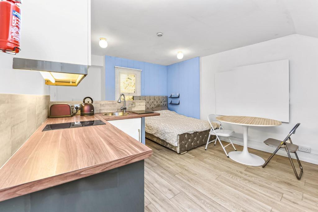 cocina y sala de estar con cama y mesa en Cosy studio flat on a budget, en Londres