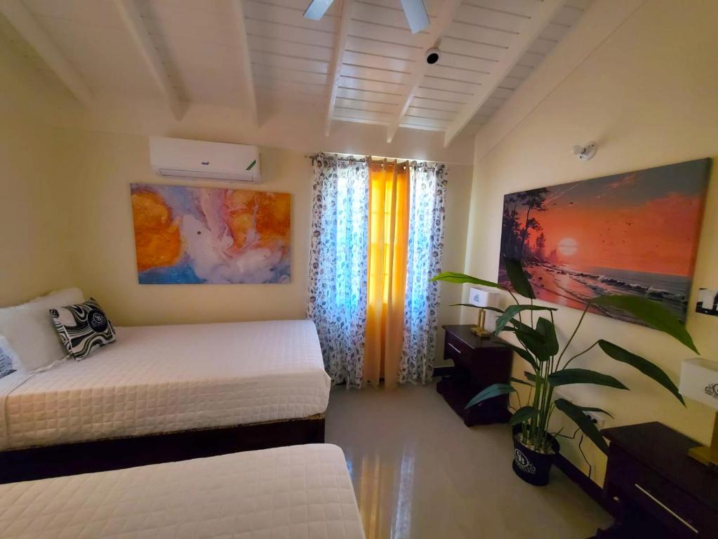 een slaapkamer met twee bedden en een plant erin bij The Surada Bay in Old Harbour
