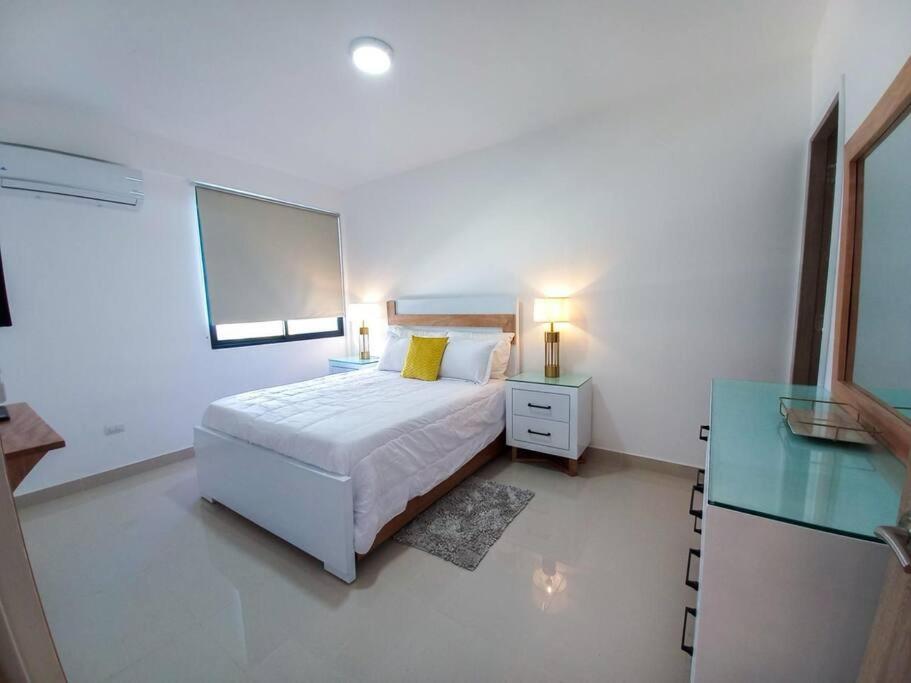 ein weißes Schlafzimmer mit einem Bett und einem Spiegel in der Unterkunft Bella Place in Santiago de los Caballeros