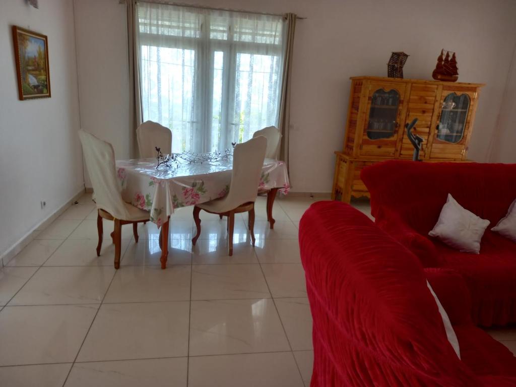 - un salon avec une table, des chaises et un canapé rouge dans l'établissement Villa mangue Julie, à Trois-Rivières
