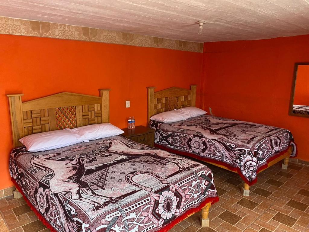 2 Betten in einem Zimmer mit roten Wänden in der Unterkunft Alex in Real de Catorce