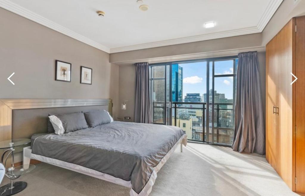 sypialnia z łóżkiem i dużym oknem w obiekcie Metropolis Dream w Auckland