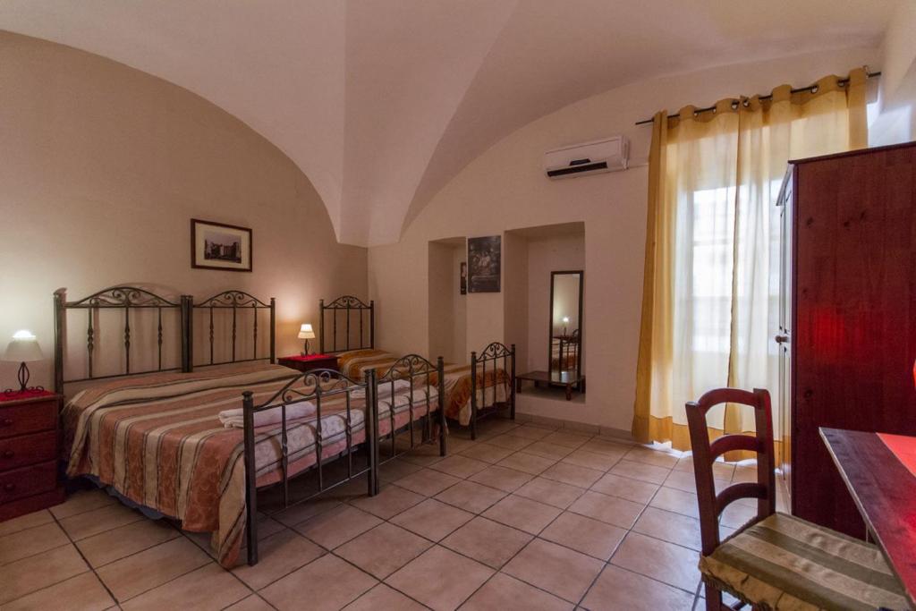 1 dormitorio con 2 camas, mesa y ventana en Albatro Rooms, en Catania